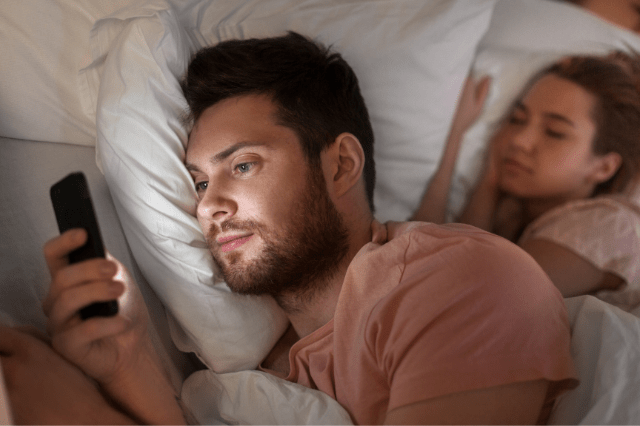 man texting to woman,while in bed with his wife
